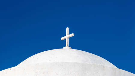Church detail, white and blue colors. Cyclades.Greece. White cross on Greek island church rooftop, clear blue sky background. Christianity religion symbol.の写真素材