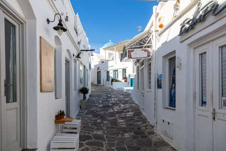 Greece, Sifnos island. May 19, 2021. Traditional greek architecture whitewashed buildings and narrow cobblestone streets, sunny day, clear blue sky. Closed shops, empty streetsのeditorial素材