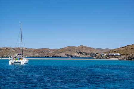 Kythnos island, Cyclades, Greece. May 27, 2021. Kolona sandy beach rocky land background. Moored...