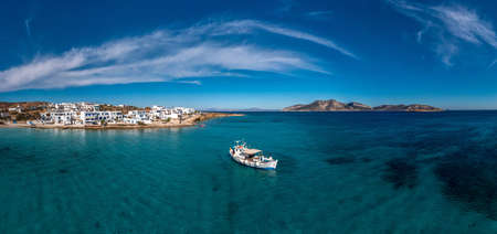 Greece, Koufonisi island aerial drone panoramic view. Traditional wooden fishing boat moored, calm emerald sea water and blue sky background. Summer holidays and relaxation at small Cycladesのeditorial素材