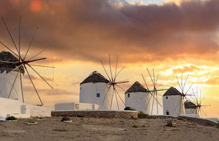 Traditional windmills, Mykonos island landmark at sunset, Cyclades Greece. Orange colors cloudy sky background. Summer holidays destinationの写真素材