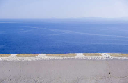 Calm sea, clear blue sky, view over a white stone parapet wall. Spectacular view to Aegean Sea, Cyclades Greece. Folegandros island outlook terrace. Copy space, summer vacations card templateの写真素材