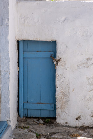 Cyclades Greece. Small blue color door on a whitewashed wall. White typical house, closed locked entrance at Kimolos island, Chora Chorio village. Traditional architecture. Summer travel destinationの写真素材