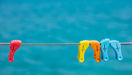 Clothespins on empty clothes line, blur blue color background. Colorful plastic pins hanging on boat stainless rail. Summer vacations and sailing, clothes wash and dry. Space, advertise templateの写真素材