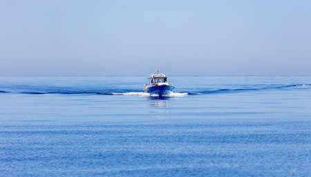 Motor boat navigating on rippled Aegean sea background, trail on calm water. Greece, Cyclades. Still...