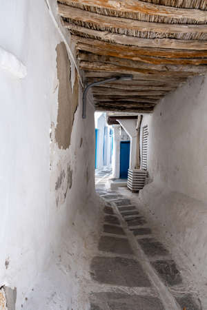 Mykonos island, Greece, Cyclades. Narrow street in Chora town. Traditional stone paved covered alley called stegadi. Whitewashed walls, Cycladic architecture in white and blueの写真素材