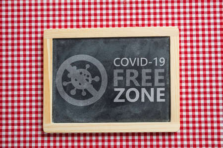 Covid free zone sign. COVID 19 FREE ZONE text label on red checkered background. Tavern, restaurant...