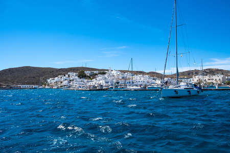 Milos island, Adamas port marina, Cyclades Greece. May 17, 2021. Sailing boat anchored at the harbor dock, cityscape, rippled sea, blue sky, view from the seaのeditorial素材