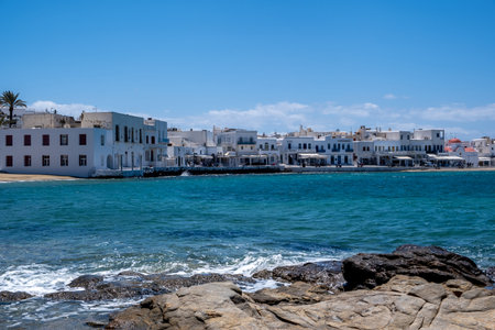 Mykonos, Cyclades, Greece. May 21, 2021. Waterfront buildings and blue sky at famous Greek island port. Summer cosmopolitan resort destination for vacation.のeditorial素材
