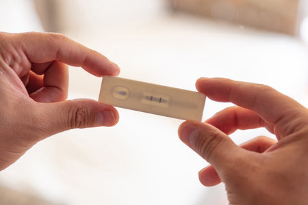 Coronavirus self testing at home, Man hands holding covid 19 positive result rapid test, kit for...