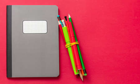 School supplies, Grey color notebook and pencils  on red color background, top view, copy space, template. Education, Back to School, kids creativity concept.の写真素材
