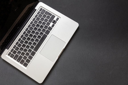 Laptop computer on black color background. Open laptop keyboard metal silver top view. Home office...