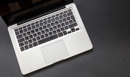 Computer laptop on black color background. Open laptop keyboard metal silver top view. Home office...