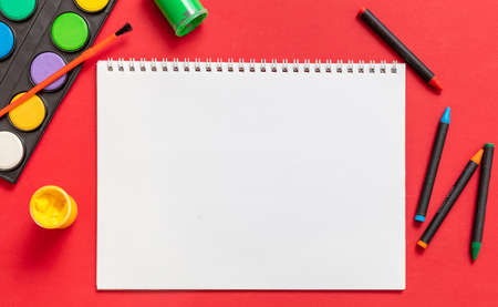 Creative kids, painting and drawing. Colorful paints and brushes on red color background, empty blank paper, copy space, template. Education, Back to School concept.の写真素材