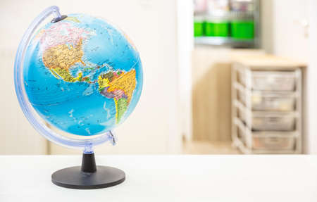 Globe school planet Earth on student desk, blur room interior background. Education, cartography, countries and world political map, back to school conceptの写真素材