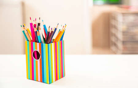 Pencils colored in a holder on student desk, blur room interior background. Education, back to school, kids creativity concept. Copy space, templateの写真素材