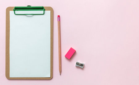School supplies, student desk top view, Blank paper clipboard, pencil eraser and sharpener on pink background, copy space, template.の写真素材