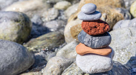 Zen balance stones, smooth pebble tower stacked on wet rocks background, sunny day on the rocky seashore. Harmony and peace by the seaの写真素材