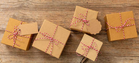 Christmas gift boxes, brown kraft paper holiday presents with red white striped string tied bow on...