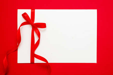 Gift card white blank with red ribbon bow on red background, Empty note paper, copy space, message...