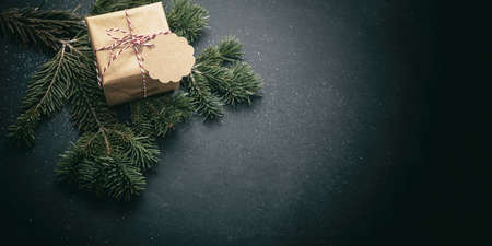 Christmas present. Xmas kraft paper gift box and fresh fir twig on black background, winter holiday...