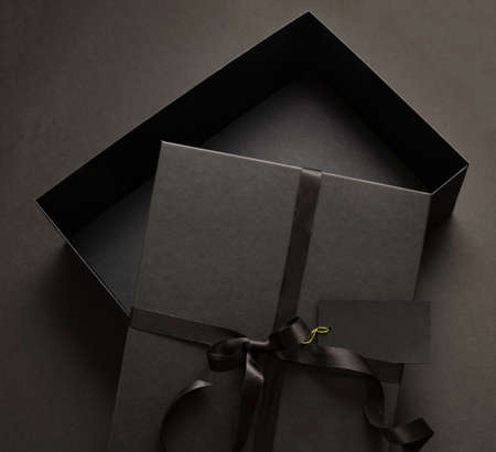 Black Friday sale concept, Gift box open cover tied with ribbon bow and empty tag on black...
