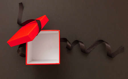 Gift box red open and ribbon bow on black background, Black Friday sale concept. Winter season holiday promotion offer template, top view, spaceの写真素材
