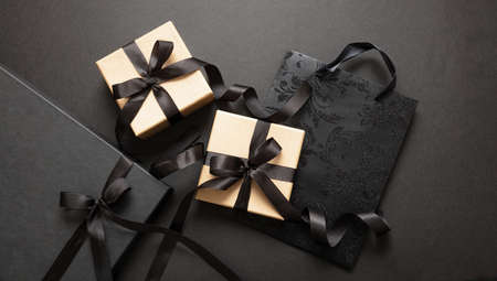 Black Friday sale concept, Gift boxes and shopping bags with tied ribbon bow on black background,...