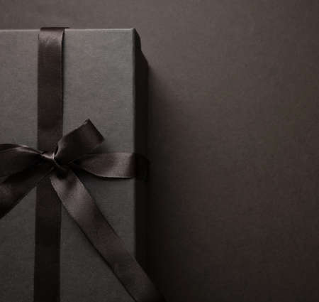 Gift box tied with ribbon bow against black background, Black Friday sale concept, Winter season holiday promotion offer template, top viewの写真素材