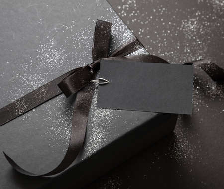 Gift box detail ribbon bow and empty tag on black background. Black Friday sale concept, Winter...