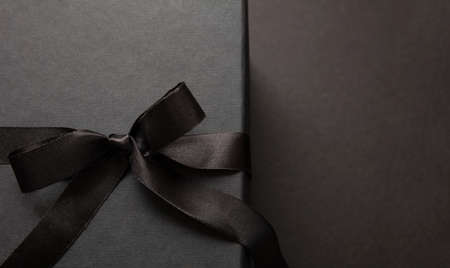 Black Friday sale concept, Gift box tied with ribbon bow against black background, closeup view, space. Winter season holiday promotion offer template, top viewの写真素材