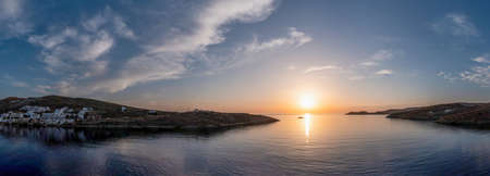 Panoramic view of Merihas port at Kythnos island, Cyclades summer destination Greece. Sunset over whitewashed houses sunbeams color the calm sea and the blue sky. Advertisement. Bannerの写真素材