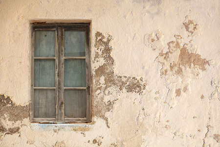 Derelict home concept. Window covered with inside wooden planks weathered aged peeled empty pink wall background. Abandoned shabby worn exterior building. Blank, copy space.の写真素材