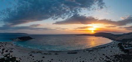 Elafonisos island, Greece. The famous double sandy beach Simos at sunset, aerial drone view. Colorful cloudy sky, rippled sea Lakonia, Peloponnese.の写真素材