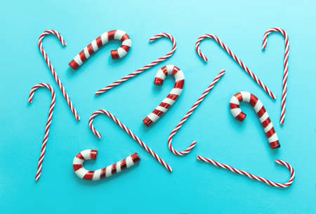 Christmas candy canes on pastel blue background. Merry Xmas concept. Peppermint red white striped traditional kids candies flat lay, pattern.の写真素材