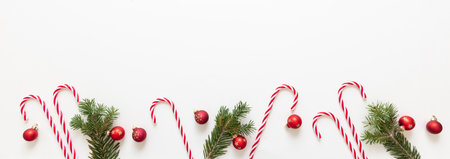 Christmas decoration border isolated on white background. Fresh fir twig, red baubles and candy...