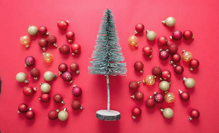 Christmas tree and decoration balls on red color background. Xmas baubles red and gold color. Merry Xmas New Year celebration, top viewの写真素材