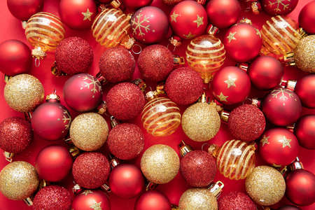 Christmas balls on red color background. Xmas baubles variety, red and golden colors, top view....