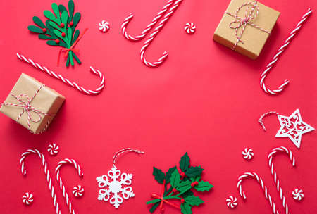 Christmas decoration frame on red color background. Gifts, baubles and candy canes flat lay. Merry Xmas New Year greeting card template, top viewの写真素材