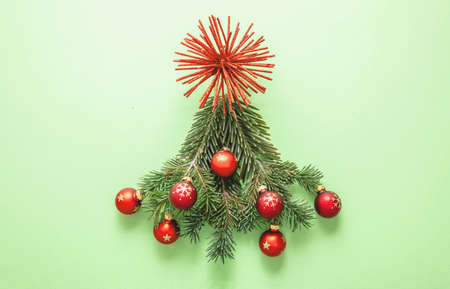 Christmas tree, fresh fir twigs and red baubles decoration on pastel green background. Merry Xmas New Year greeting card templateの写真素材