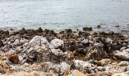 Empty rocky beach with dark and white rough rocks blue calm sea at Gerolimenas village Mani Laconia...