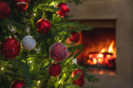 Christmas warm cozy burning fireplace, winter holiday home background. Xmas tree decoration, season greetings card templateの写真素材