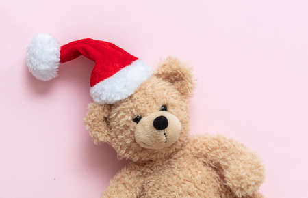 Christmas present. Teddy bear wearing Santa hat on pink color background, Kids holidays gifts, toys and stuffed animals. Holiday greeting card.の写真素材