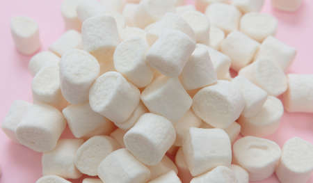 Marshmallows heap on pastel pink background. White fluffy mini dessert, sweet kids birthday party snack, closeup viewの写真素材