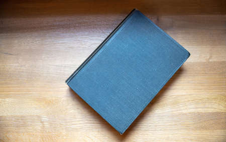Closed old black notebook on wooden background, top view. Blank cover book on a table. Copy space, hardcover templateの写真素材