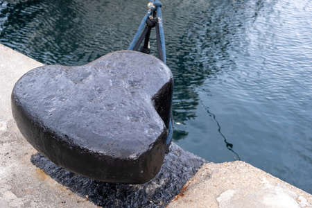 Ship mooring rope around a port bollard on harbor pier, rippled sea water background, copy space....