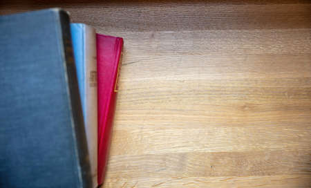 Books stack on a table. Closed old notebooks on wooden desk background, top view. Copy space, templateの写真素材