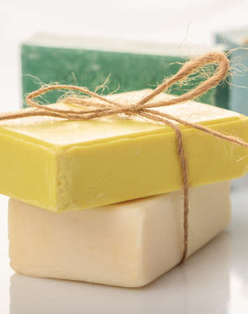 Handmade soap bars tied with rope on white background. Luxury green, yellow, pink bath soap from...
