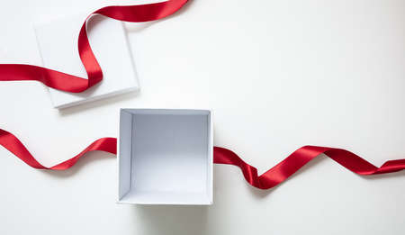 Overhead of open white box and red satin ribbon isolated on white, empty space. Valentine day gift, Christmas present, curly decoration.の写真素材