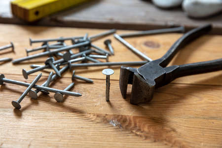 Pincers and nail stack on wood. Carpenter work bench table, closeup view, joinery workshopの写真素材